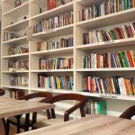 a library filled with lots of books next to wooden tables