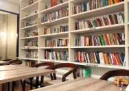 a library filled with lots of books next to wooden tables
