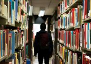 man with backpack beside a books