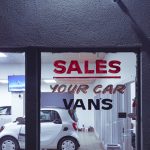 a car dealership with a sales sign in the window