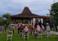 people sitting on chairs near brown wooden house under white clouds during daytime