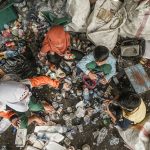 A pile of garbage with people standing around it