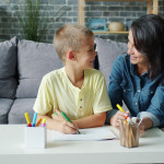 Mother and son drawing at a table together.
