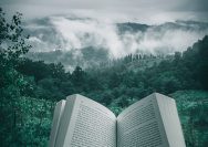 person holding open book viewing mountain view